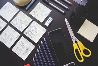 Um smartphone, post-its, canetas e lápis — ferramentas para prototipagem rápida de um designer.