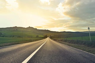 A road that is passing through a grassy field.