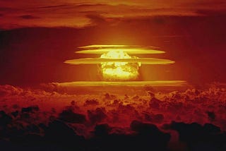 frightening mushroom cloud rising in a blood red sky — caused by a nuclear bomb test by the US Military in the western Pacific in 1954