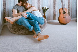 couple snuggling on bean bag with guitar nearby