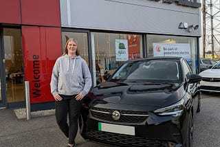 Sophie stood next to her Vauxhall Corsa-E outside the Vauxhall dealership.