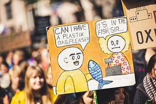 Cartoon: Boy buying a fish asks, “Can I have a plastic bag please?” Shop assistant responds: “It’s in the fish sir.” (Comment on environmenal pollution.)