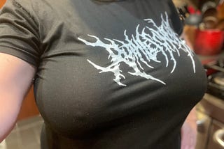 Selfie of the author’s boobs in a black t-shirt with white writing