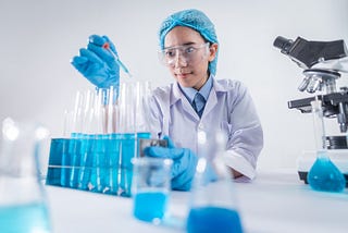 A female scientist adding chemicals to test tubes with a dropper