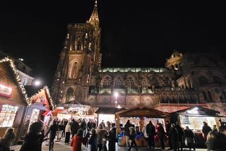 Strasbourg Christmas Market lit up at night with the Gothic Cathedral in the background.