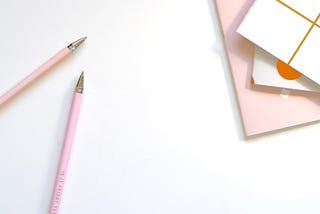 Pens, pencils, and notebooks on a table.