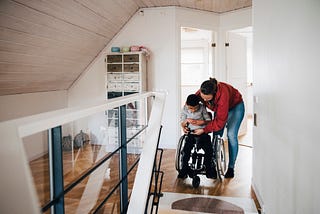 Woman fastening wheelchair buckle for disabled child at home