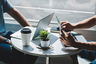 Two people with laptops working in a coffee shop.