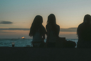 three women watching the sunset by the water, the third slightly out of frame
