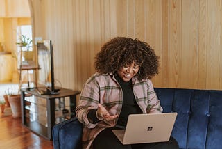 A woman sitting on a blue chair using a laptop