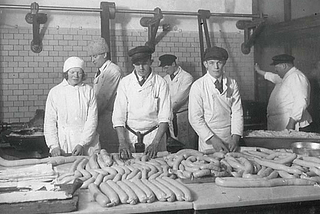 Black and white photograph of three Swedish sausage makers displaying their products — entitled, in Swedish, Korvtillverkning på Slakthusområdet