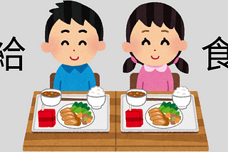 A little boy and girl sitting at a table, each with their own 給食 (a nutritionally balanced meal made by the school that all children eat together).