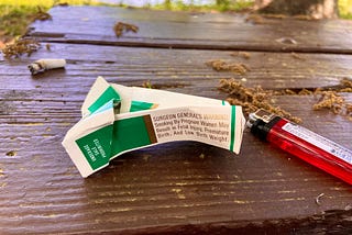 A cigarette butt, lighter, and a crumpled pack of cigarettes.
