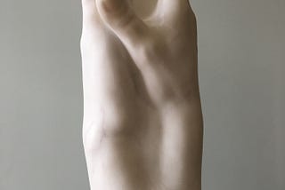 Sculpture in white marble, two right hands joined like a spire reaching towards the sky