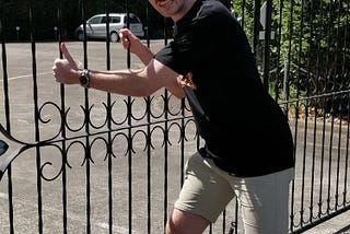 Man shaking large iron gate with two hands grasping it