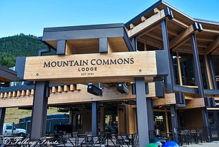 “Mountain Commons Lodge Est 2024” on a mass timber building outside of the Crystal Mountain Ski Resort. Trees in the background.