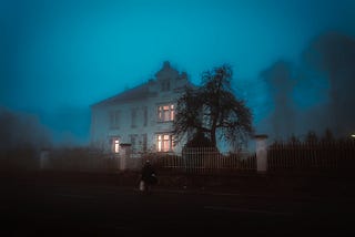 Mansion in the dark, with lit interior.