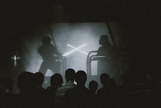 A crowd of people indoors watching Star Wars movie and rock music concert on a projector