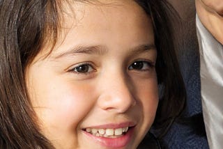 An adolescent girl with brown hair and eyes smiling off to the side