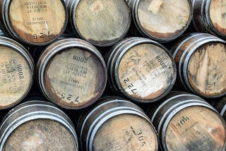 Stacks of whiskey barrels with their batch info and year stamps imprinted on their faces