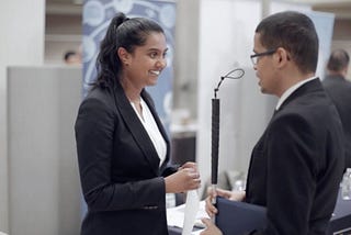 Recruiter Sharon Singh speaks with a man holding a white cane.