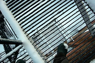 The view of a snow-covered fire escape, looking down.