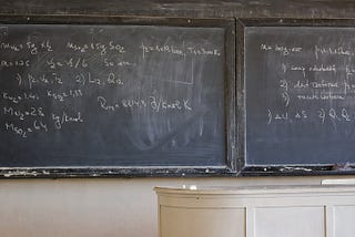 Blackboard with extensive mathematics equations in front of an old desk