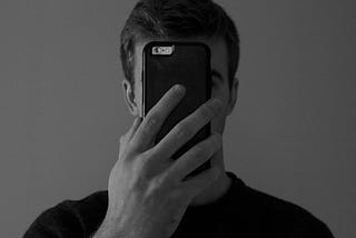 A man scrolls on a phone covering his face
