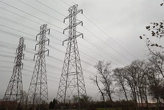 Power lines tower over a dark landscape