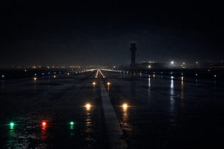 Dark, wet airport runway at night.