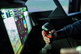 View of glass cockpit display and a hand on an aircraft’s joystick