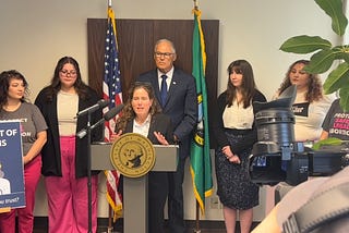 Photo of woman standing at podium with group of people behind them.