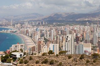 A view of the city of Benidorm, Spain, highlighting the contrast between its high-rise architecture and the surrounding countryside