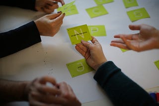 A group of people holding green cards with adjectives describing the differentiators for the solution they design.