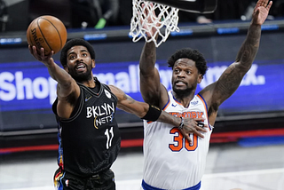 Brooklyn Nets guard Kyrie Irving drives for a layup past Knicks forward Julius Randle