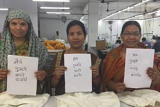 “Maine tumhare kapde banaye” I made your clothes in Hindi is hand written on signs held up by fair trade garment workers. But the signs weren’t written by them. Two in the photo are not literate.