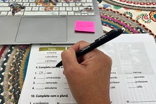 Computer keyboard and printed sheets from a textbook in Portuguese