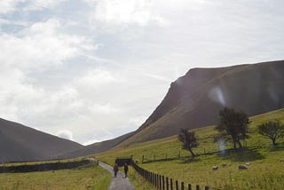 Two walkers on a track leading into the Lake District mountains