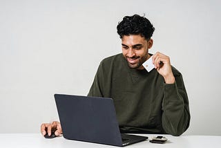 Man sitting at a laptop holding a credit card.