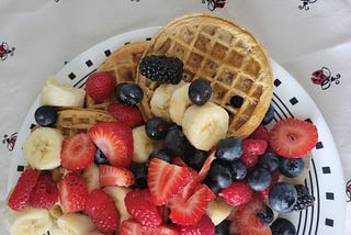 Circular toaster waffles topped with a heap of mixed fruit