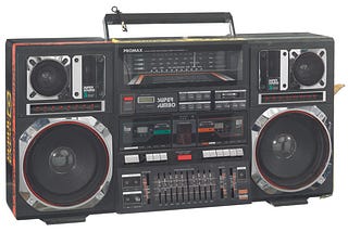A Promax Super Jumbo boombox (2014.270.2.1a) used as a prop by the character Radio Raheem in the Spike Lee directed picture, “Do the Right Thing”. The boombox includes a dual audio casette tape deck, an equilizer section, radio dial, colored light display, and a pair each of 8" subwoofers, midranges, and tweeters. There are sections of red, yellow, and green electical tape with black ink text on the sides and top of the player. There are also rectangular black, green, and yellow “Public Enemy” s