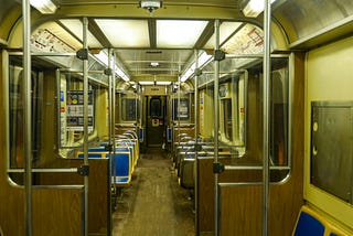 the inside of a subway train lined with empty seats