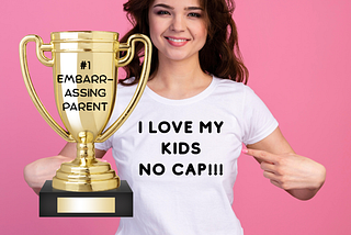 A woman with a shirt that says “I love my kids no cap” and a trophy that says #1 embarrassing parent