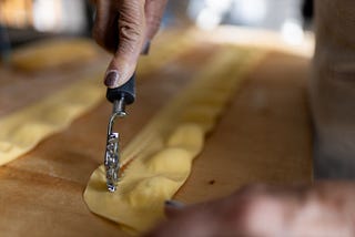 Cutting the flattened yellowish dough on the wodden board