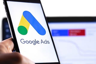 Google Ads logo on smartphone with notebook in background