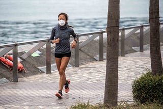 A young woman with a face mask jogs along the waterfront in Hong Kong,