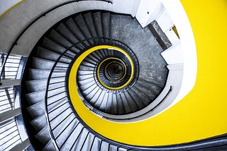 Looking down a spiral staircase with a yellow background.