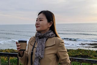 Felicia Wu holds a cup of coffee looking ahead on the Half Moon Bay coastline.