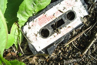 An old cassette tape thrown away in the dirt