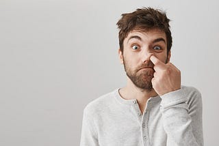 A man digging his nose, looking funny. Picking booger or snot.